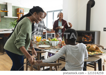 Happy african american multi generation family serving food at thanksgiving dinner 121314259