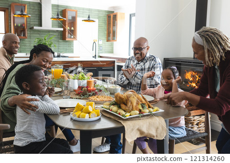 Happy african american multi generation family serving food at thanksgiving dinner 121314260
