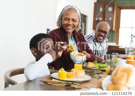 Happy african american grandmother serving food for grandson at thanksgiving dinner 121314276