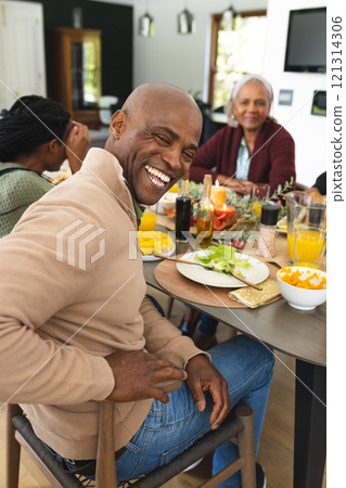 Portrait of african american father with family laughing at thanksgiving dinner table 121314306