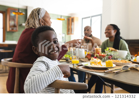 Portrait of african american son with family smiling at thanksgiving dinner table 121314332
