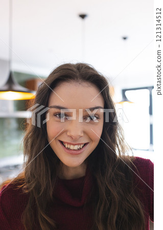 Portrait of happy caucasian woman with long brown hair smiling in kitchen at home 121314512
