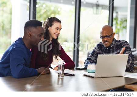 Diverse couple and biracial male financial advisor using laptop and discussing documents at home 121314534