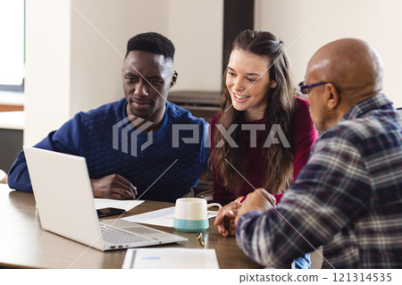 Diverse couple and biracial male financial advisor using laptop and discussing documents at home 121314535