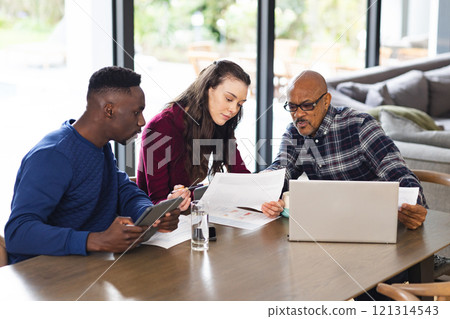 Diverse couple and biracial male financial advisor using laptop and discussing documents at home 121314543