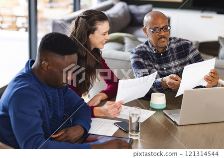 Diverse couple and biracial male financial advisor using laptop and discussing documents at home Diverse couple and biracial male financial advisor using laptop and discussing documents at home 121314544