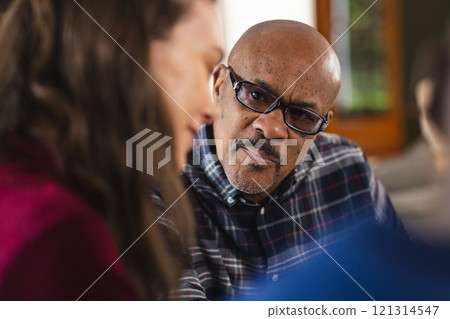 Diverse couple and biracial male financial advisor talking at home 121314547