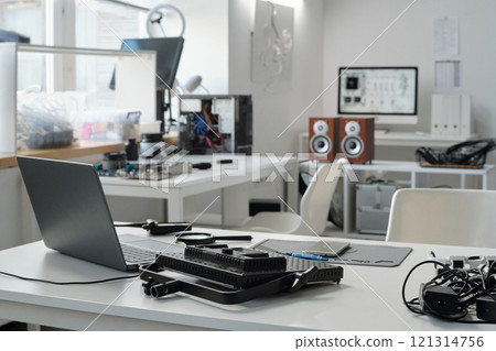 Modern office featuring advanced technology and gadgets. Various devices and electronic equipment are visible on desks, contributing to a high-tech and organized workspace 121314756