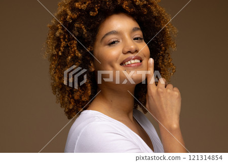 Happy biracial woman with dark curly hair touching face and smiling Happy biracial woman with dark curly hair touching face and smiling 121314854