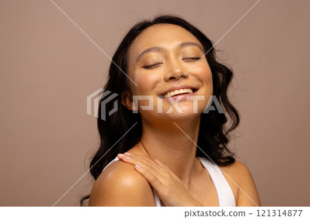 Happy asian woman with dark hair, with hand on shoulder and eyes closed 121314877