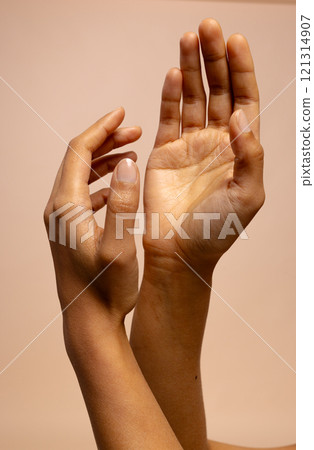 Crossed arms and reaching hands of biracial woman on pink beige background with copy space Crossed arms and reaching hands of biracial woman on pink beige background with copy space 121314907