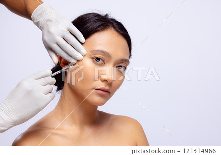 Hands of beautician in white surgical gloves injecting botox in cheek of asian woman, copy space Hands of beautician in white surgical gloves injecting botox in cheek of asian woman, copy space 121314966