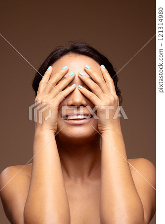 Smling asian woman with dark hair wearing blue nail varnish with hands over eyes 121314980