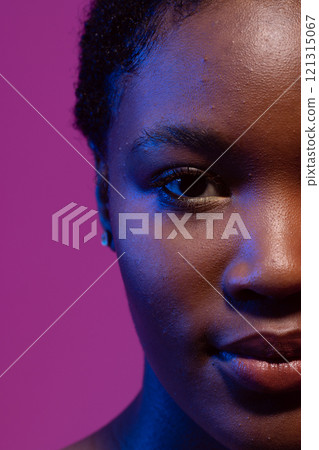 Half portrait of african american woman with short hair in blue light, purple background 121315067