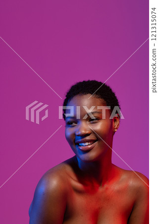 African american woman looking away smiling, in blue and red light on purple background, copy space African american woman looking away smiling, in blue and red light on purple background, copy space 121315074