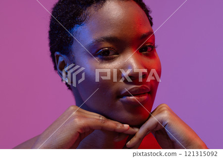 African American woman, short hair, hands under chin, red and blue light, purple background 121315092