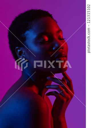 African american woman touching chin with eyes closed in red light on purple background African american woman touching chin with eyes closed in red light on purple background 121315102