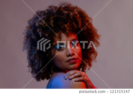 Biracial woman with curly hair and hand on shoulder in blue and red light Biracial woman with curly hair and hand on shoulder in blue and red light 121315147