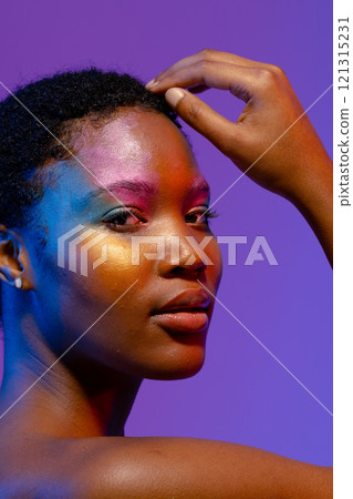 African american woman with short hair and colourful make up touching head 121315231
