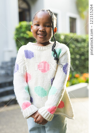 Portrait of happy african american girl with braids standing outside house 121315264