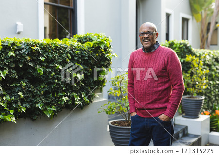 Portrait of happy senior african american man wearing glasses standing outside house, copy space Portrait of happy senior african american man wearing glasses standing outside house, copy space 121315275