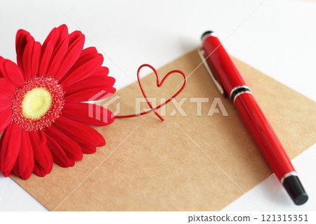 Red gerbera and brown message card, red fountain pen, red heart wire 121315351