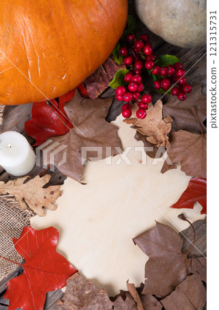 Paper with copy space, autumn leaves, pumpkin and berries on wooden surface against wooden surface Paper with copy space, autumn leaves, pumpkin and berries on wooden surface against wooden surface 121315731