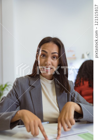 Smiling biracial businesswoman sitting at desk making video call in modern office 121315817