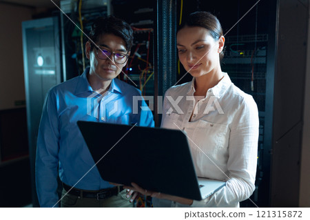 Diverse male and female engineers using laptop in computer server room Diverse male and female engineers using laptop in computer server room 121315872