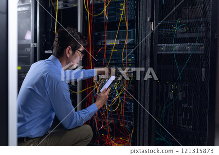 Asian male engineer using digital tablet and inspecting computer server in computer server room 121315873