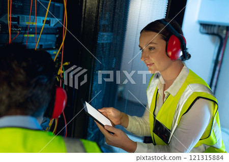 Caucasian female engineer using digital tablet while inspecting in computer server room Caucasian female engineer using digital tablet while inspecting in computer server room 121315884