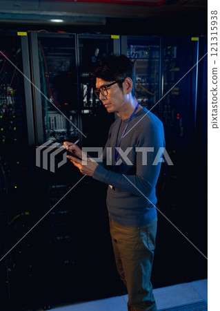 Asian male engineer writing on clipboard in computer server room Asian male engineer writing on clipboard in computer server room 121315938