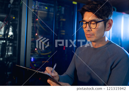 Asian male engineer writing on clipboard in computer server room Asian male engineer writing on clipboard in computer server room 121315942