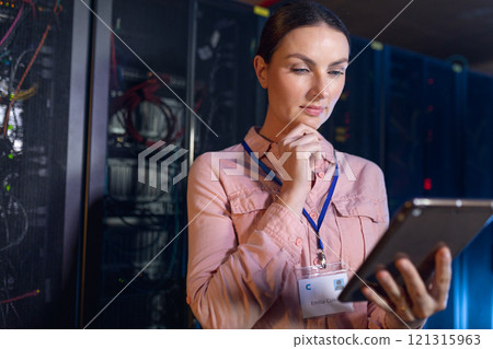 Thoughtful caucasian female engineer using digital tablet in computer server room Thoughtful caucasian female engineer using digital tablet in computer server room 121315963