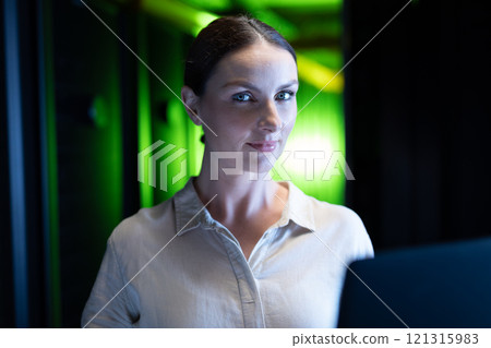 Portrait of caucasian female engineer with laptop in computer server room 121315983