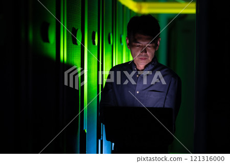 Asian male engineer using laptop in computer server room Asian male engineer using laptop in computer server room 121316000