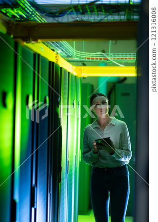 Caucasian female engineer using digital tablet while inspecting in computer server room Caucasian female engineer using digital tablet while inspecting in computer server room 121316008