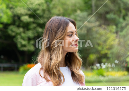Smiling woman enjoying peaceful moment in lush green park setting 121316275