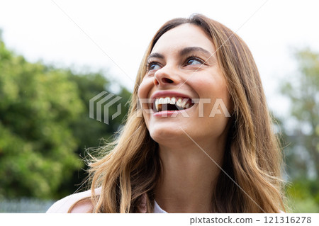 Smiling woman enjoying outdoors, looking up with joy and happiness Smiling woman enjoying outdoors, looking up with joy and happiness 121316278