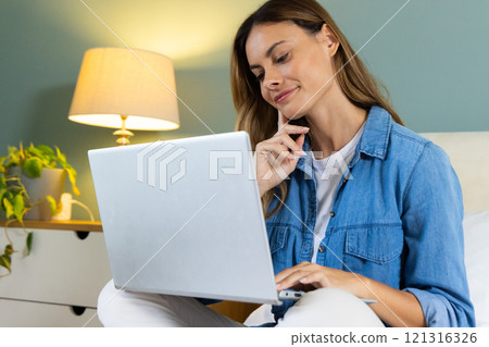 At home, woman using laptop and smiling, feeling relaxed and content 121316326