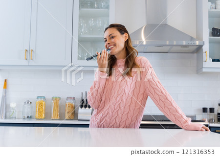 Smiling woman in kitchen singing into microphone, enjoying festive moment, at home Smiling woman in kitchen singing into microphone, enjoying festive moment, at home 121316353