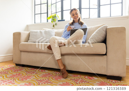 At home, woman shopping online with tablet and credit card, feeling relaxed At home, woman shopping online with tablet and credit card, feeling relaxed 121316389