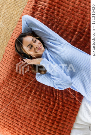 Relaxing at home, woman in blue sweater enjoying music with headphones 121316420