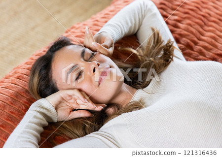 Relaxing at home, woman enjoying peaceful moment on cozy blanket 121316436