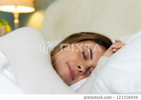 Woman peacefully sleeping in cozy bed, enjoying restful night at home 121316439