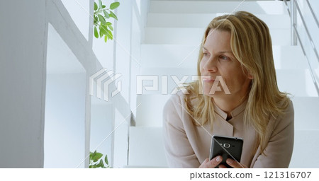 Beautiful woman using mobile phone on stairs at home 4k Beautiful woman using mobile phone on stairs at home 4k 121316707