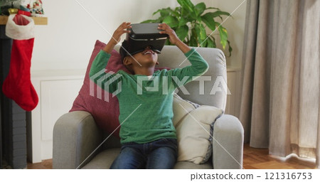 Happy african american boy wearing vr headset and having fun at christmas time 121316753