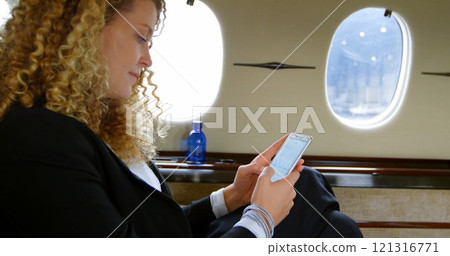 Beautiful businesswoman using mobile phone in private jet 4k 121316771