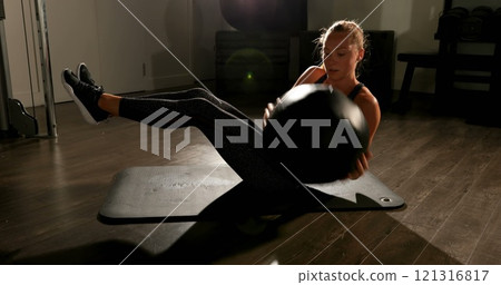 Side view of Caucasian female athlete practicing twist exercise in fitness studio 121316817