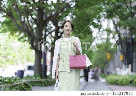 一位中年婦女在綠樹叢中購物 121317953